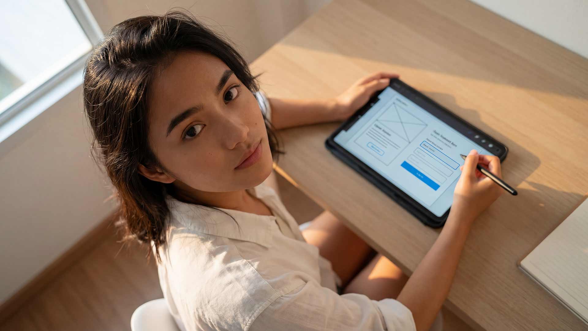 Siyu reviewing website design from overhead angle with tablet in Phuket office