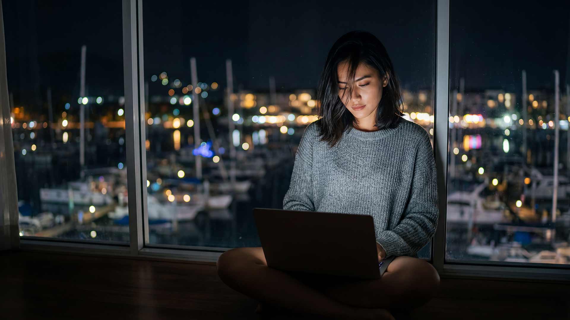 SEO specialist working on laptop with Phuket marina view at night